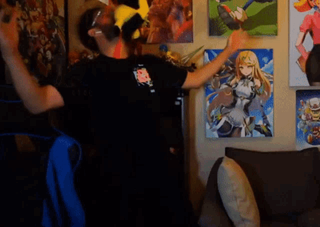 a man in a black shirt is dancing in front of a couch and a painting of a girl on the wall .