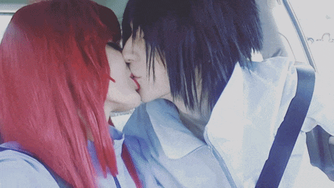 a woman with red hair kisses a man with black hair