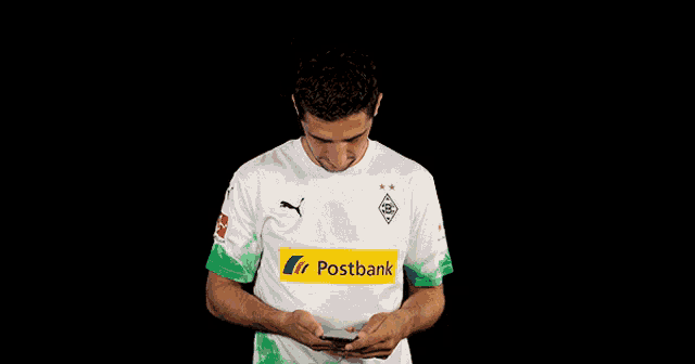 a man wearing a postbank shirt is giving a thumbs up