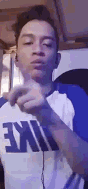 a young man wearing a nike shirt is making a face .