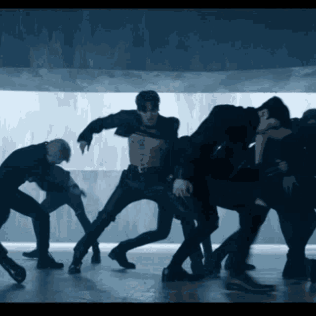 a man without a shirt is surrounded by other men in black