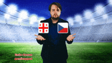 a man in a suit stands in front of a stadium with a georgian flag and a czech flag on his chest