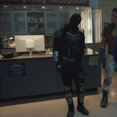 a man in a superhero costume stands in front of an emergency reception desk