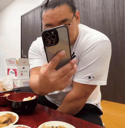 a man wearing a white shirt with a mlb logo is taking a selfie