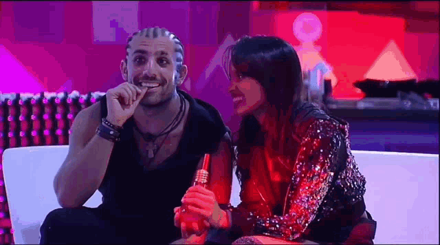 a man and a woman are sitting on a couch and laughing .