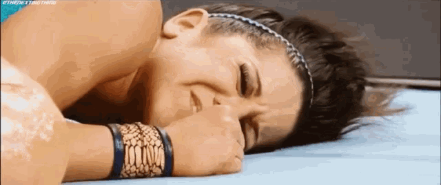 a woman is laying on the ground with her eyes closed and her hand on her face .