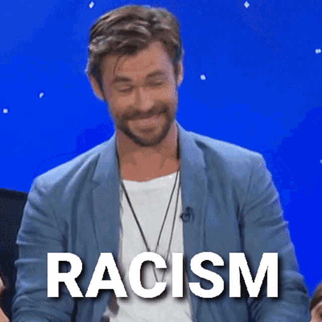 a man with a beard is smiling and the word racism is written on a blue background