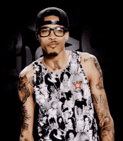 a man wearing glasses and a baseball cap is standing in front of a black background ..
