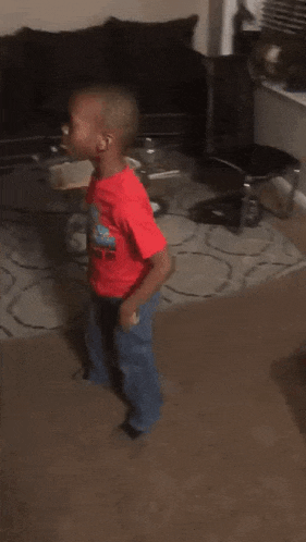 a young boy is dancing in a living room in front of a couch .
