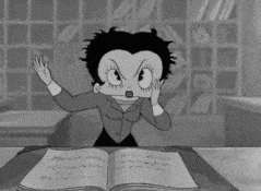 a black and white cartoon of betty boop sitting at a desk reading a book