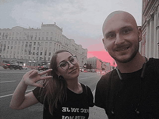 a man and a woman are posing for a picture and the woman is wearing a black shirt that says aec lot