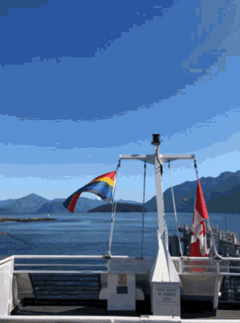 a boat with a rainbow flag and a canadian flag on the side