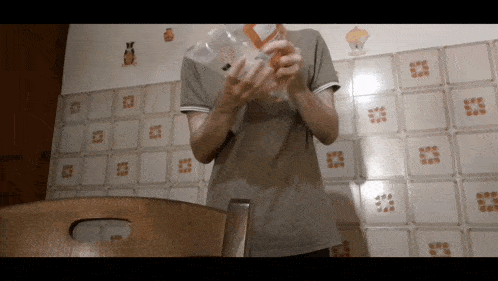 a person holding a plastic bottle in front of a tiled wall with cupcakes on it