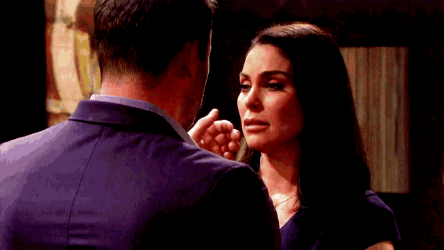 a man is touching a woman 's face while they look at each other