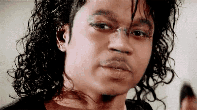 a man with long curly hair is looking at the camera .