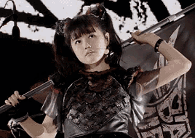 a young girl is holding a sword in front of a flag .