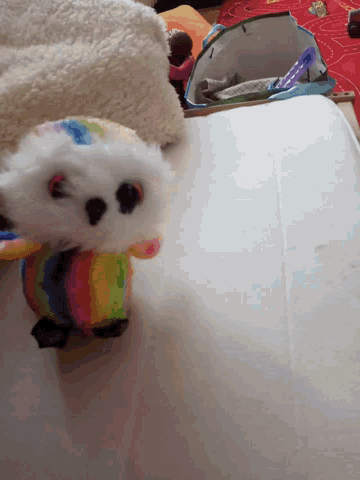 a stuffed animal with a rainbow outfit is laying on a blanket
