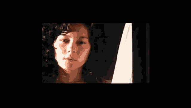 a close up of a woman 's face in a dark room with a black background .