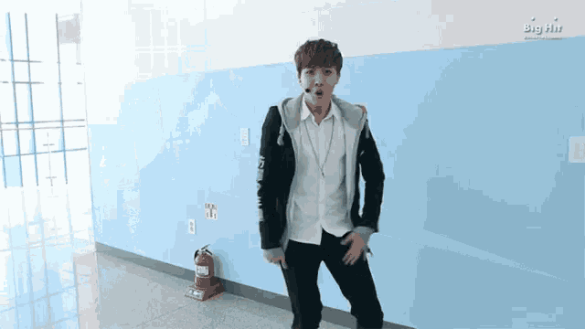a man is dancing in a hallway with a fire extinguisher on the floor .