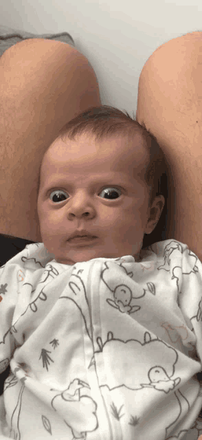 a baby is laying on a person 's lap wearing a sheep pajamas
