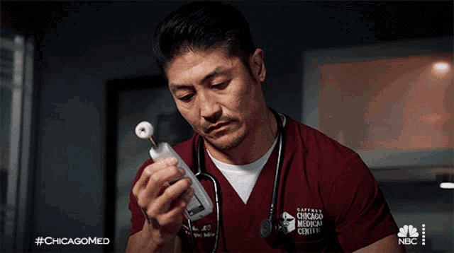 a man in a chicago medical center scrub is holding a device
