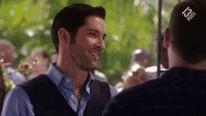 a man in a blue shirt and vest is smiling at another man in a black shirt .