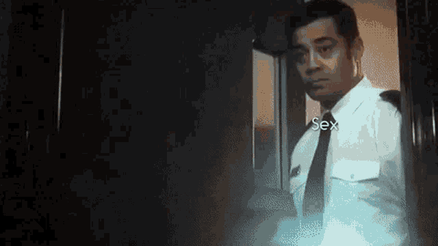 a man in a uniform and tie is standing in a doorway .