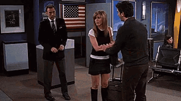 two men and a woman are standing in a room with an american flag behind them