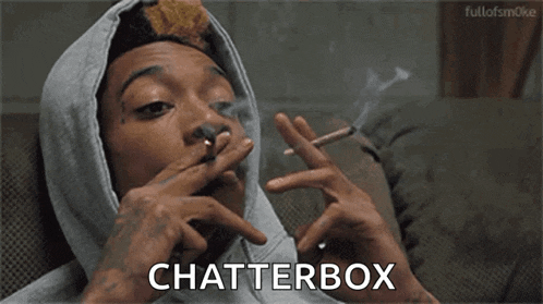 a man in a hoodie is smoking a cigarette and the word chatterbox is on the screen .