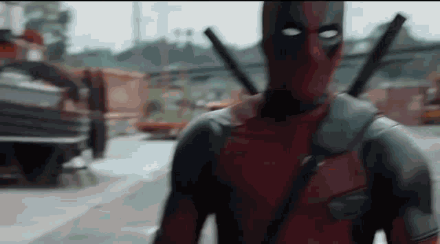 a man in a deadpool costume is walking down a street with a gun .