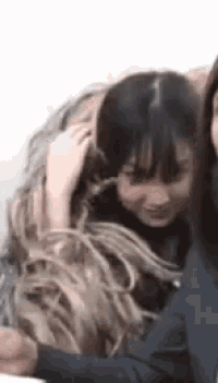 a woman is holding another woman 's hair while sitting next to her .