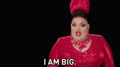 a drag queen is wearing a red dress and a red hat and ready to win this gig .