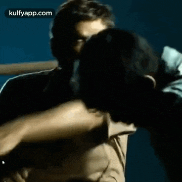 two men are standing next to each other in a dark room .