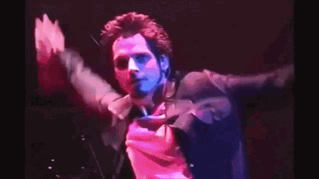 a man in a black jacket is standing on a stage with his arms in the air .