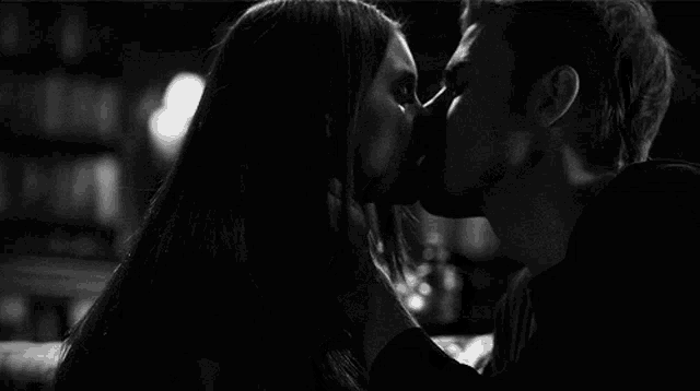 a man and a woman kissing in a black and white photo .