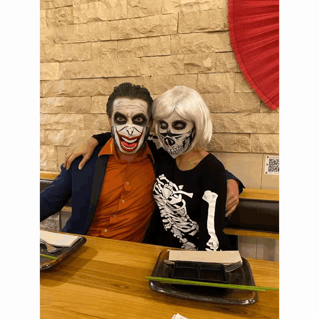 a man in a skeleton sweater and a woman in a joker costume pose for a picture