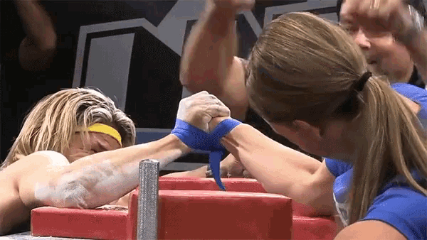 two women arm wrestling with one wearing a headband