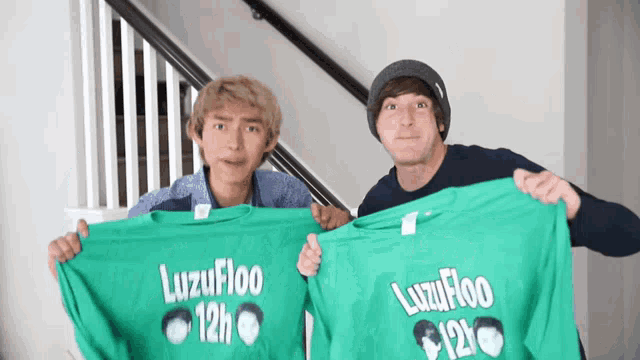 two men hold up green shirts that say luzufloo