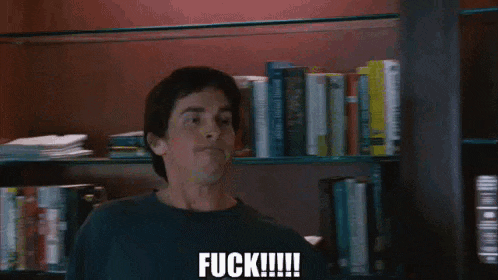 a man in a black shirt is standing in front of a shelf with a picture on it and says `` fuck '' .