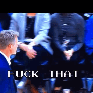 a man in a blue suit stands in front of a screen that says fuck that in white letters