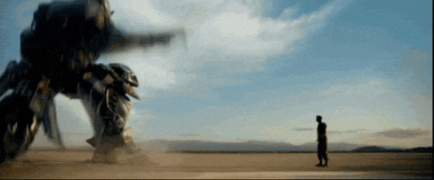 a man is standing in front of a robot in a desert .