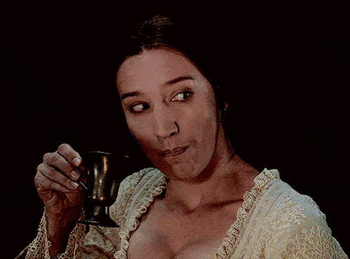 a woman with a very large breast is holding a small cup in her hand