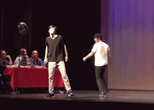 a man in a black shirt is standing on a stage in front of a group of people