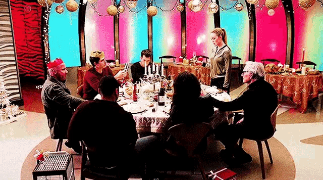 a group of people are sitting around a table with plates of food and drinks .