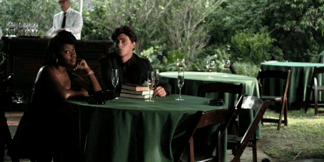 a man and a woman sit at a table with green tables cloths and chairs