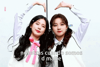 two girls are making a heart shape with their hands and the words nosotras cuando somos d maite