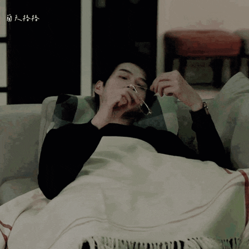 a man laying on a couch with chinese writing on the bottom right corner