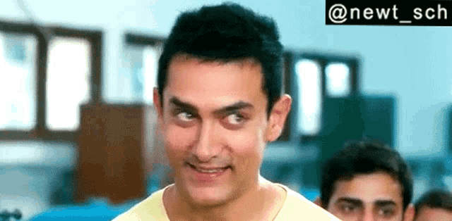 a man in a yellow shirt is making a funny face in a room with other men .