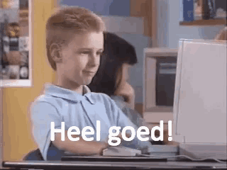 a young boy is sitting in front of a computer with the words heel goed written on the screen