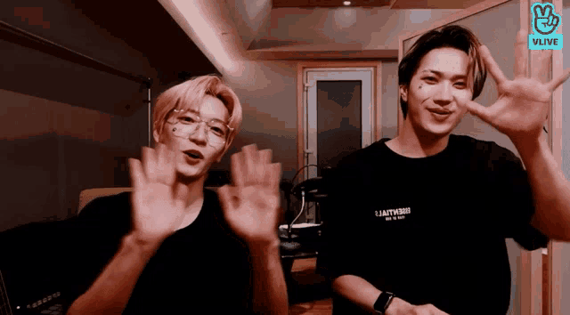 two men are waving their hands in front of a vlive screen